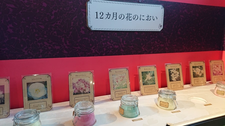 におい展の「12カ月の花のにおい」展示。月ごとの花の写真パネルと、それぞれの香りを体験できるガラス瓶が並んでいる様子。