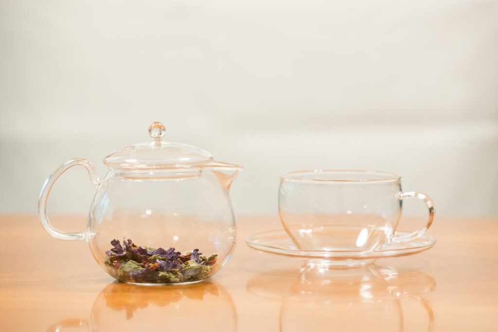 ハーブティーの茶葉が入ったガラスポットとカップが並ぶテーブルの様子