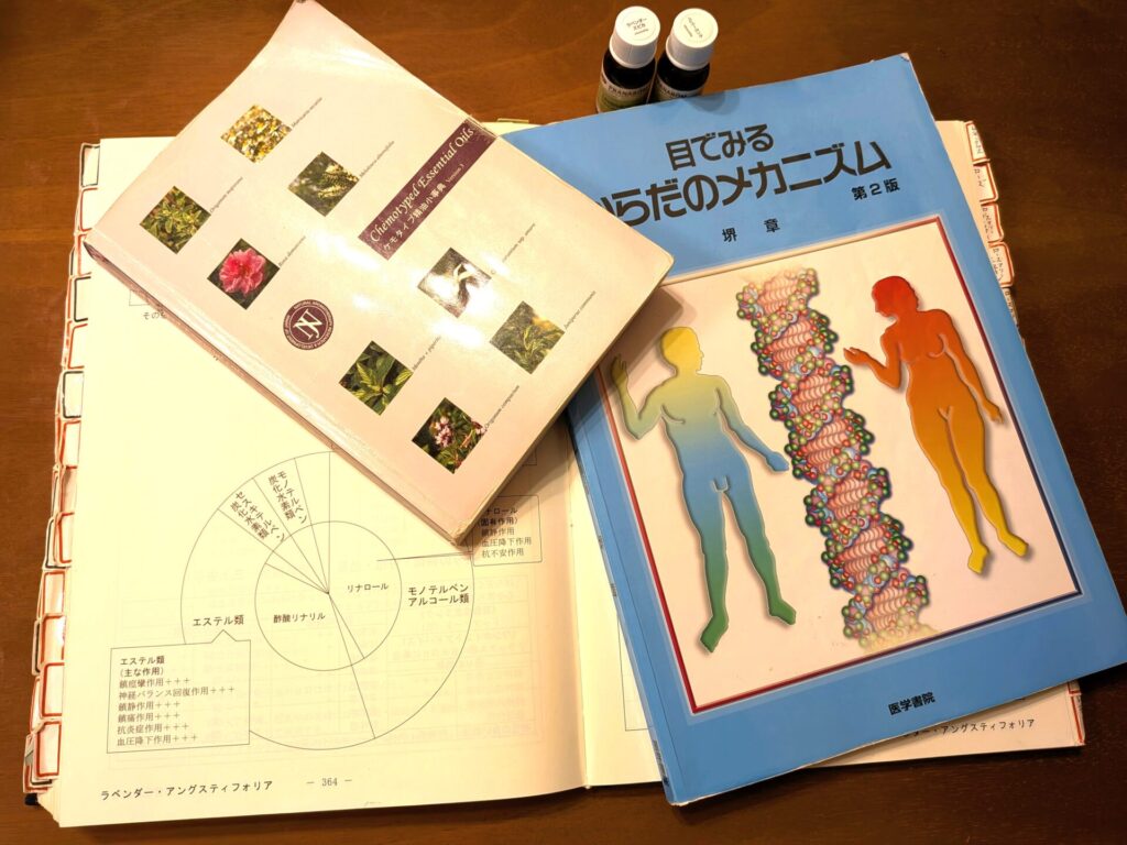 NARDアドバイザー講座で使用する精油の成分表と参考書が並ぶ勉強机の様子