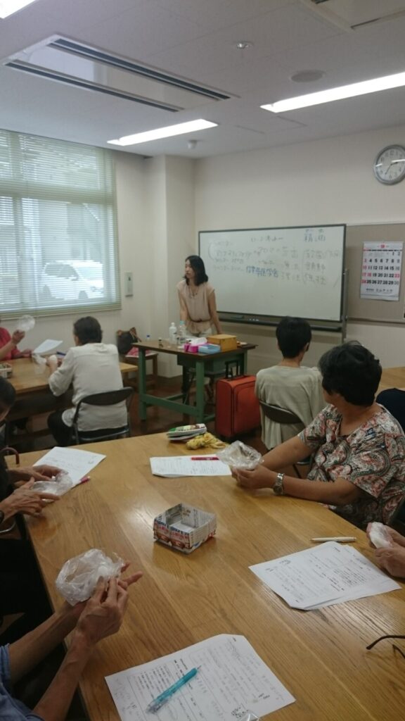 高齢者施設で行われた風ら花のアロマ石けん作り講座の様子。参加者がテーブルで石けんをこねながら学んでいる場面。