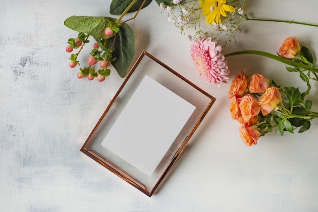 白いカードと花々を並べたナチュラルなテーブルの上のイメージ写真。安心感とやさしさを感じる構図。