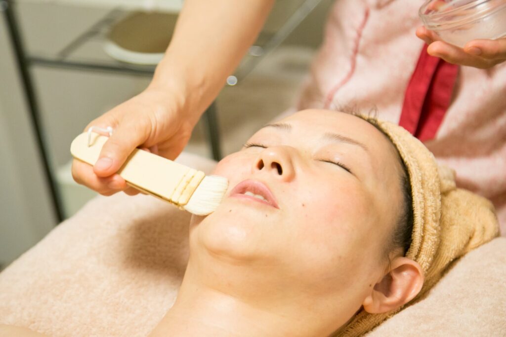 ハーブフェイシャルで鎮静パックをブラシでやさしく塗布する様子。植物の恵みで肌と心を整える自然派エステ。