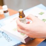 講座で使用す精油の瓶を手に持ちふたを開けた様子とアロマアドバイザーテキスト。実践的に学ぶアロマの現場をイメージさせる写真。