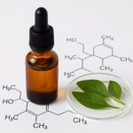 精油瓶と植物が並ぶ写真に、化学式が重ねられたアロマの化学をイメージした構図