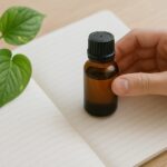 精油瓶とノート、葉を添えた手元のイメージ写真