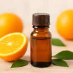 柑橘系のオレンジの果実と精油瓶が並んだ写真。アロマテラピーに使われるオレンジ精油のイメージ。