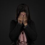 顔を手で覆って気持ちが沈んでいる女性の写真